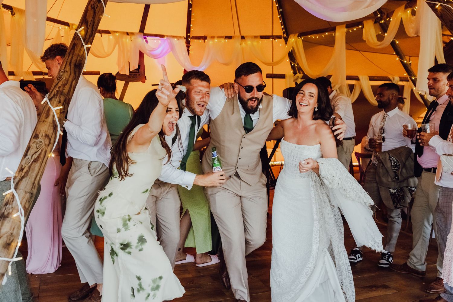 Happy wedding guests and the couple are celebrating together on the dance floor.