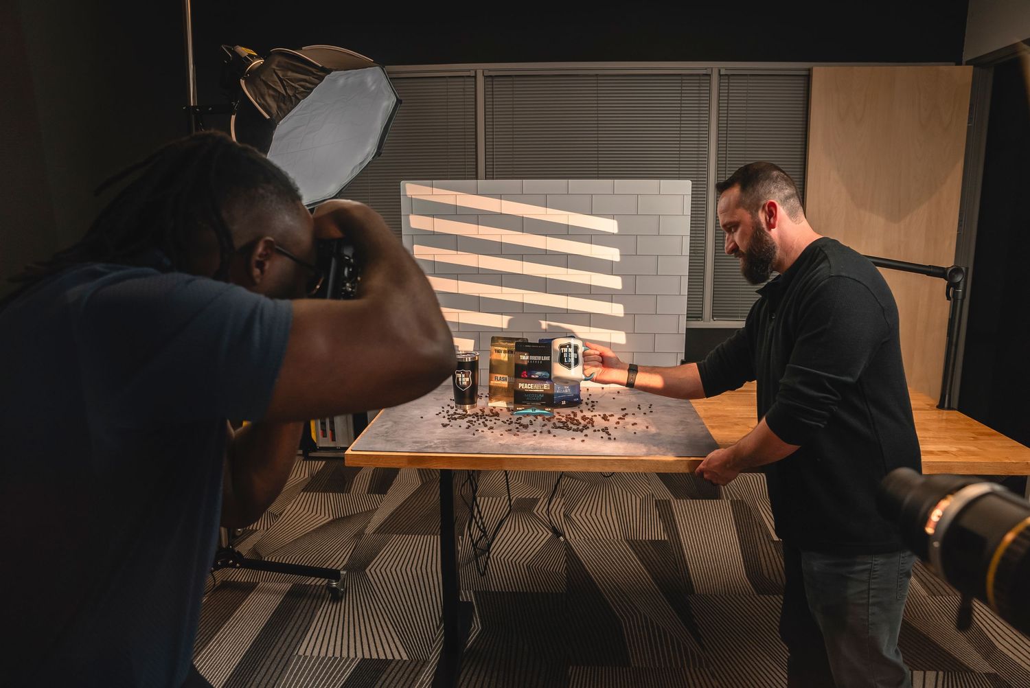 People gathered around a product photography table during dimly lit photo session.