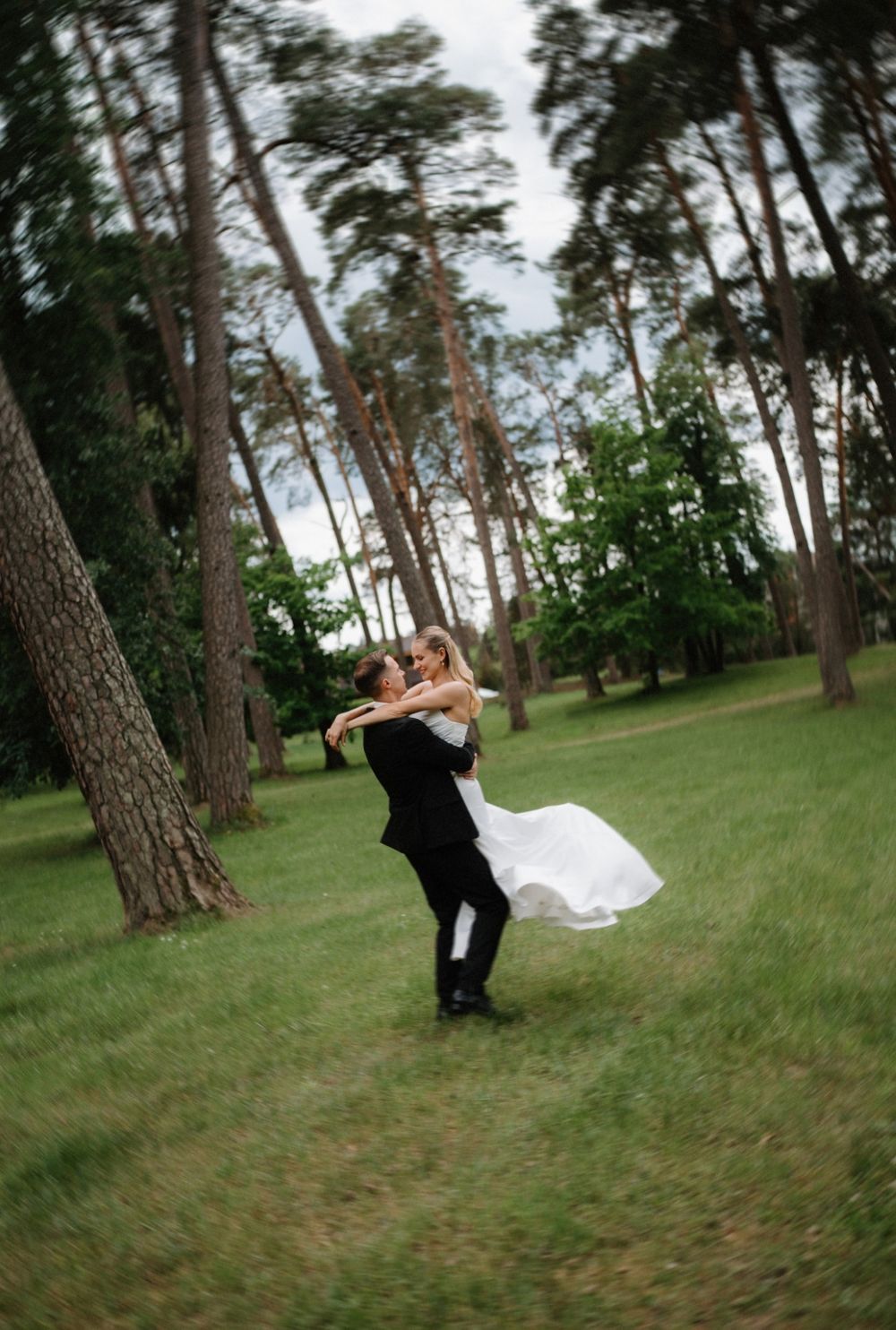 A playful sequence of a couple spinning and dancing together in a pine forest setting.