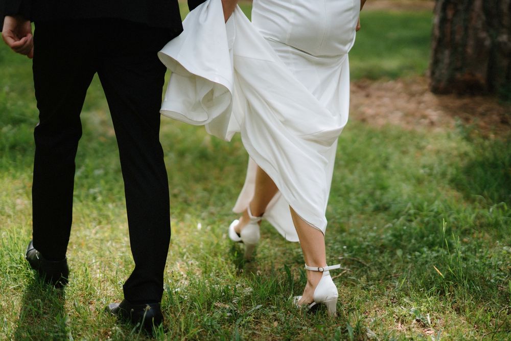 Close-up view of formal black and white attire and shoes on grass.