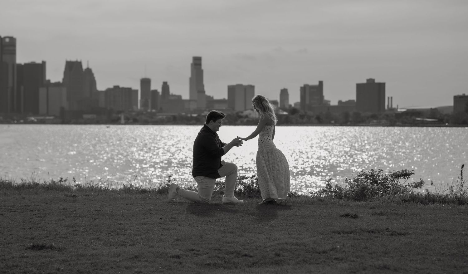 A silhouetted couple shares an intimate moment against a sunset sky in a romantic outdoor setting.