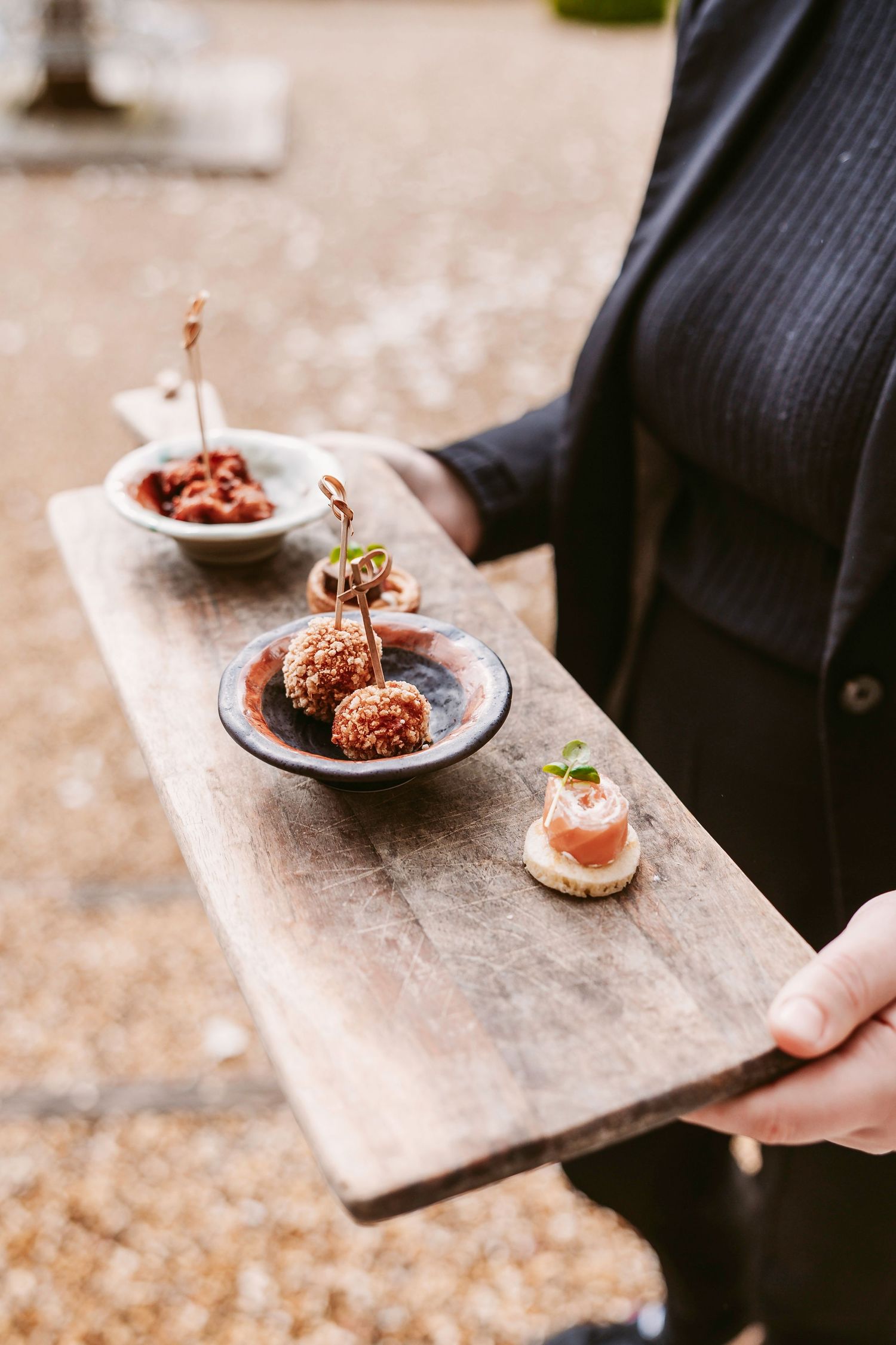 Catering staff serving gourmet appetizers on rustic wooden serving boards at an event.