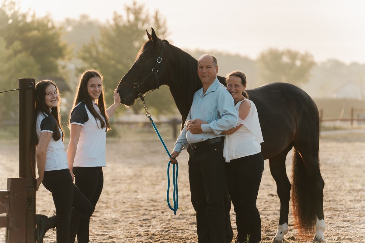 A family gathers in a sun-drenched field during golden hour for an outdoor photo session with their horse in Sydney Hills district