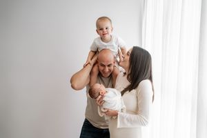 A loving family shares tender moments together in a bright white room, creating a heartwarming atmosphere.