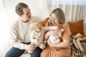 A loving family shares tender moments together on a couch in a bright, sunlit room.