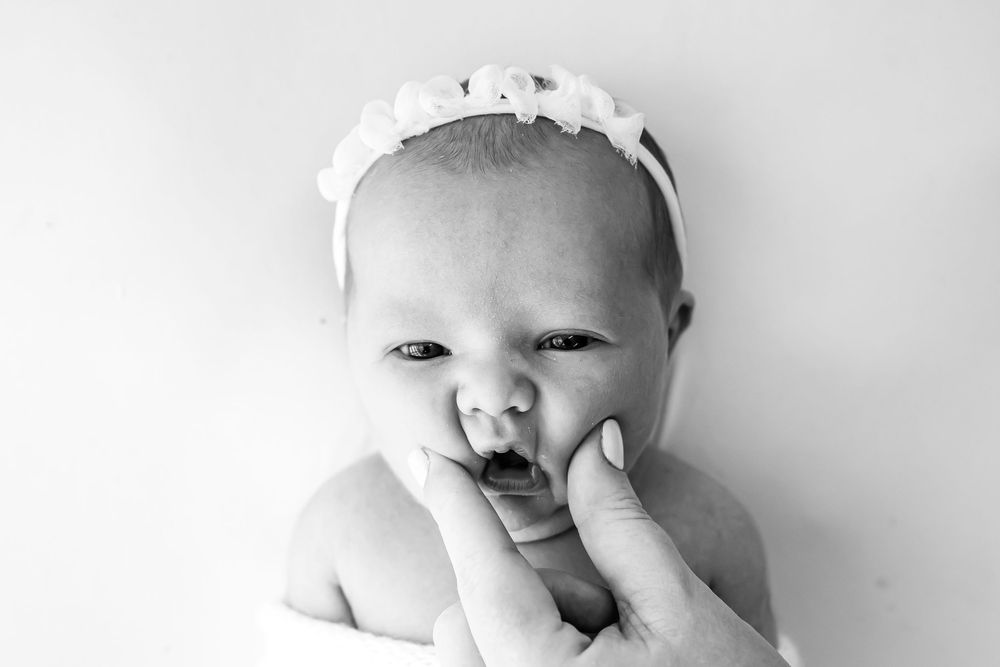 Black and white photo series showing a baby in four different candid expressions and poses.