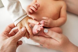 Close-up shots of tiny baby feet and hands being gently held against a white background.