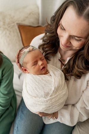 A tender moment between parent and newborn baby swaddled in white, captured in a series of intimate photographs.