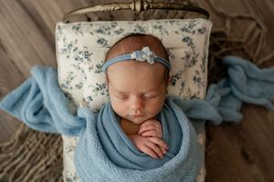 Sleeping newborn baby wearing blue headband and swaddle blanket photographed from multiple angles on textured backdrop.