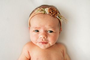 Collection of newborn baby portraits with soft lighting and delicate headband accessories on white background.