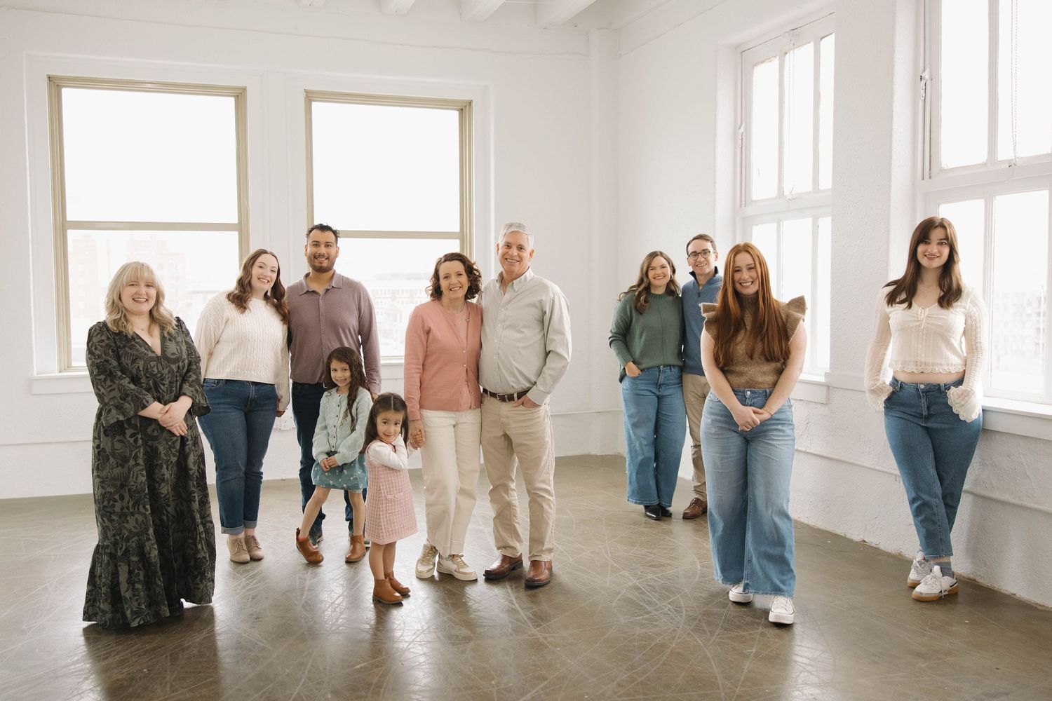 A group of people stand in a bright white studio space during what appears to be a dance or movement class.