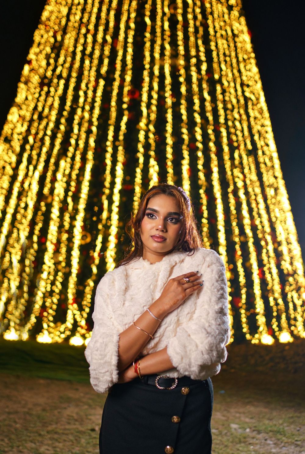 Fashion portrait with cascading golden string lights creating a dramatic backdrop.