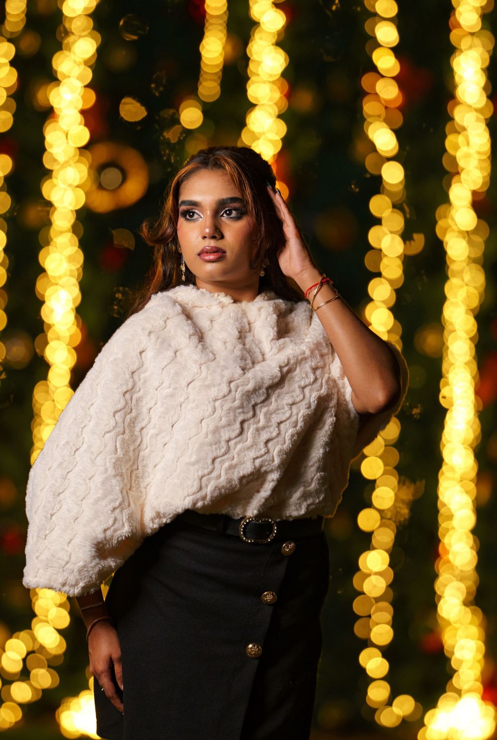 Fashion portrait with white fur collar against glowing golden bokeh lights backdrop creating dramatic ambiance.
