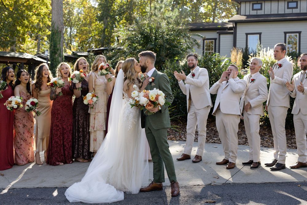 Wedding party in white and burgundy attire poses together outdoors.