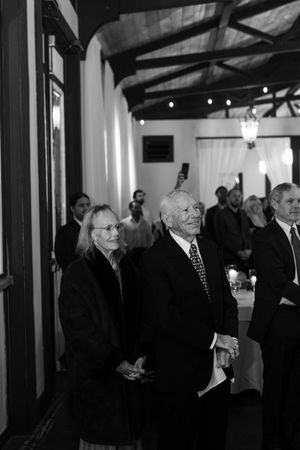 Black and white photo of formal reception gathering in elegant indoor venue.
