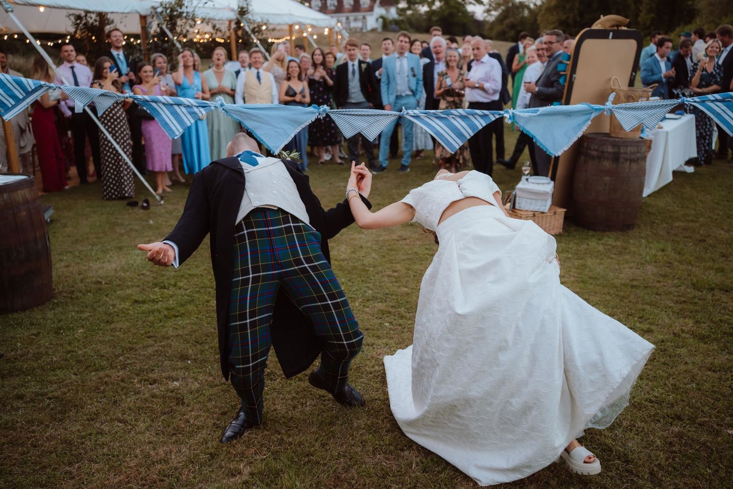 A couple shares a romantic dance at an outdoor wedding reception as guests watch and celebrate their special moment.