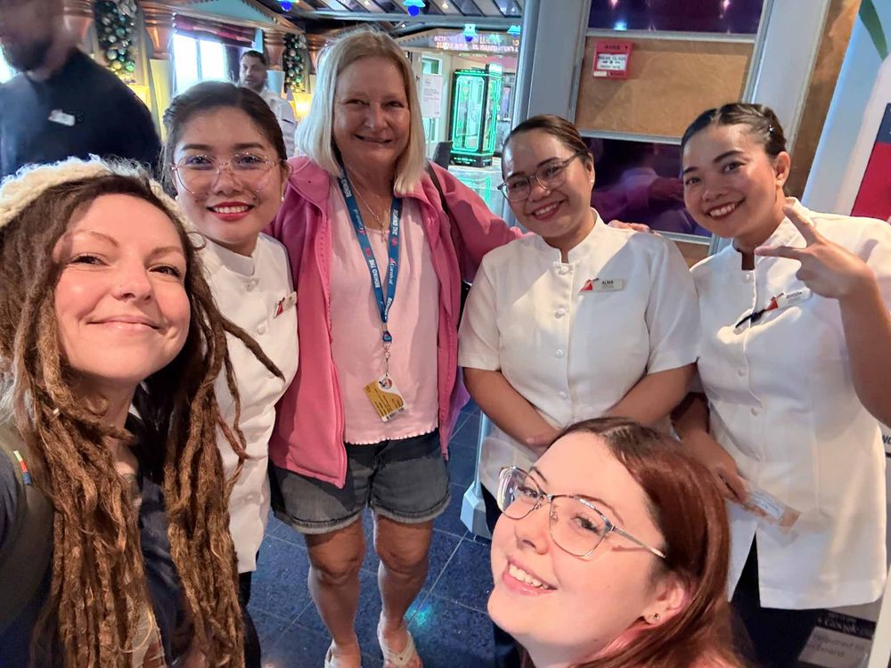 A group of people smiling and posing together in what appears to be a casual indoor setting.