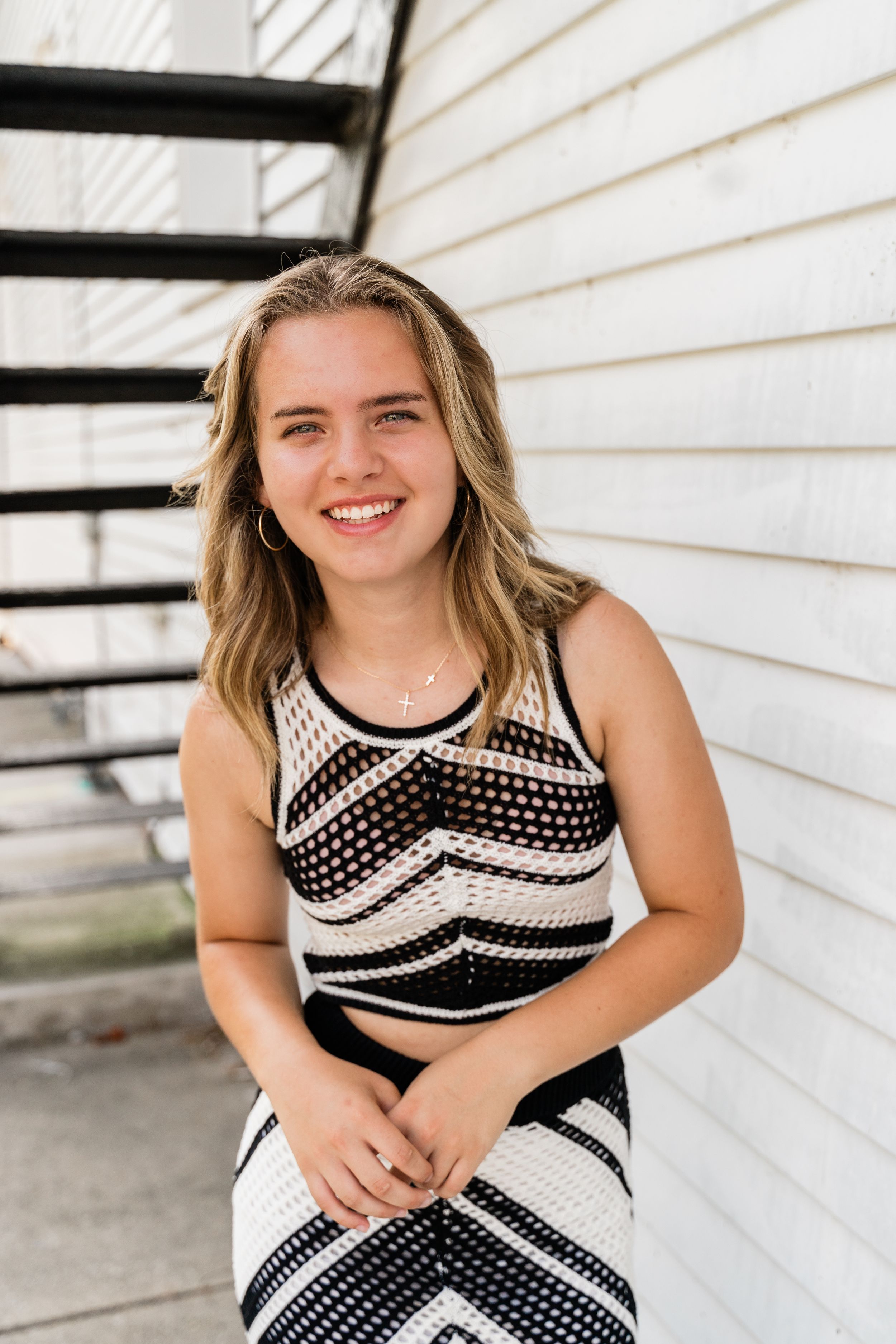 A black and white polka dot dress is shown in a series of photos against white siding backdrop.