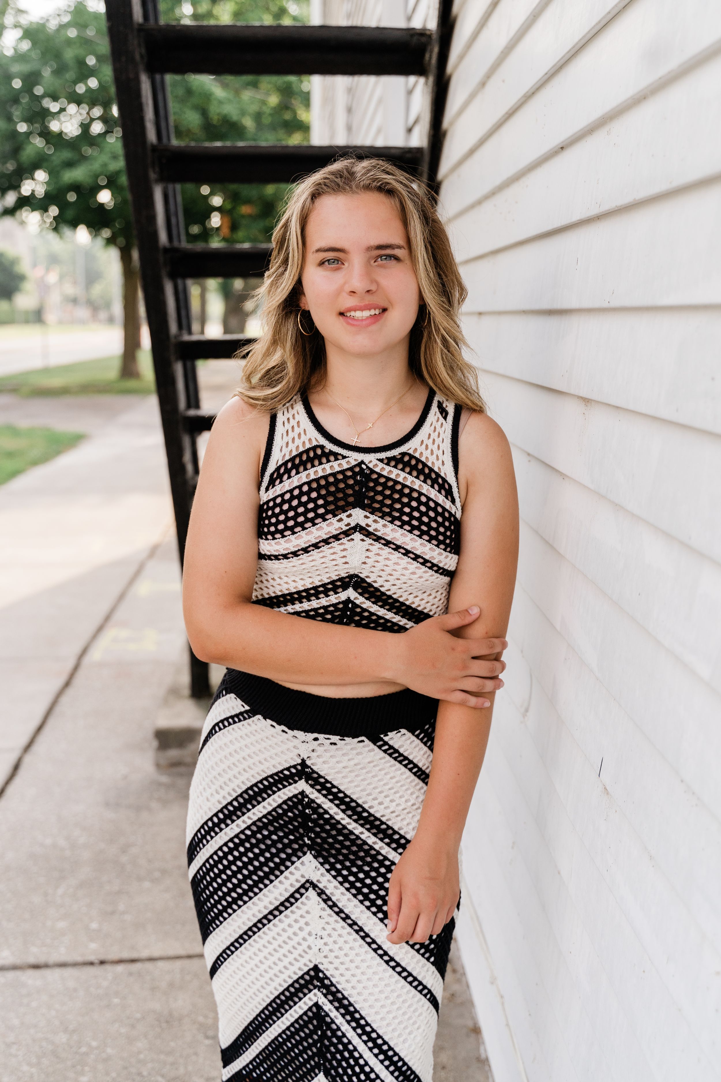 A geometric black and white dress is photographed against white siding and greenery.