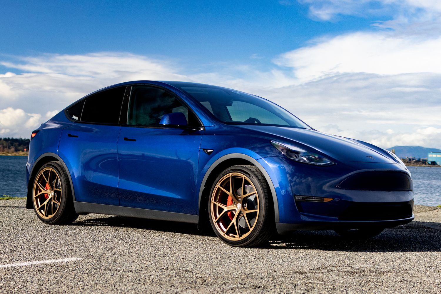 A sleek blue sports car shown from multiple angles on a paved surface against a bright sky background.