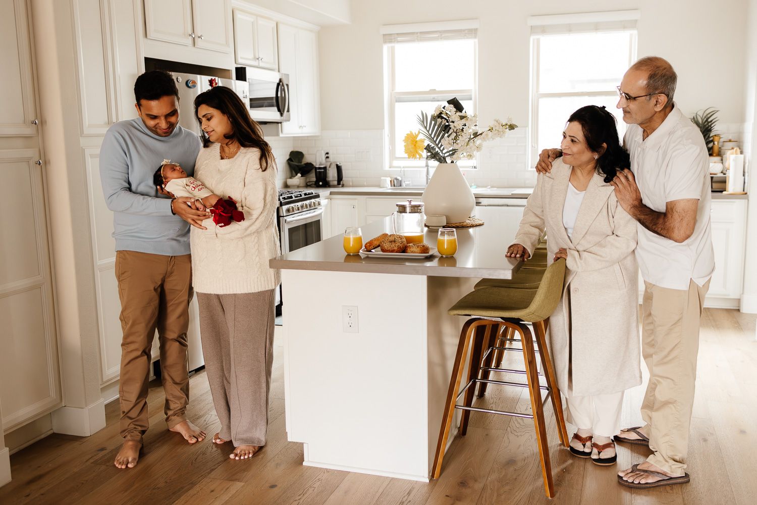 Parents and grandparents gather in the kitchen for a celebration with their new baby