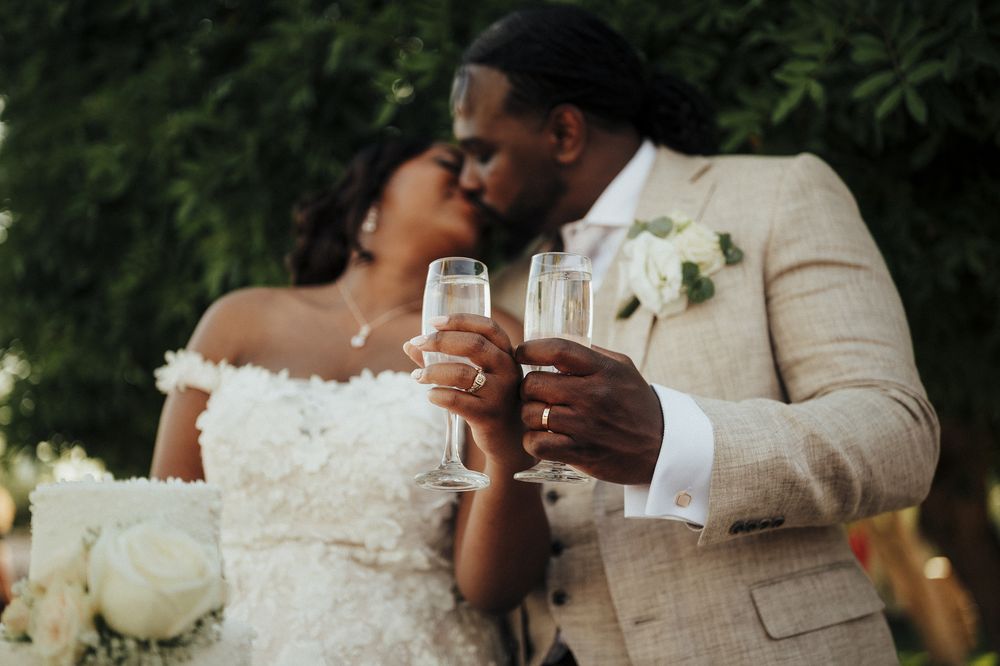 A romantic wedding couple shares intimate moments in a garden setting while wearing elegant cream and white attire.