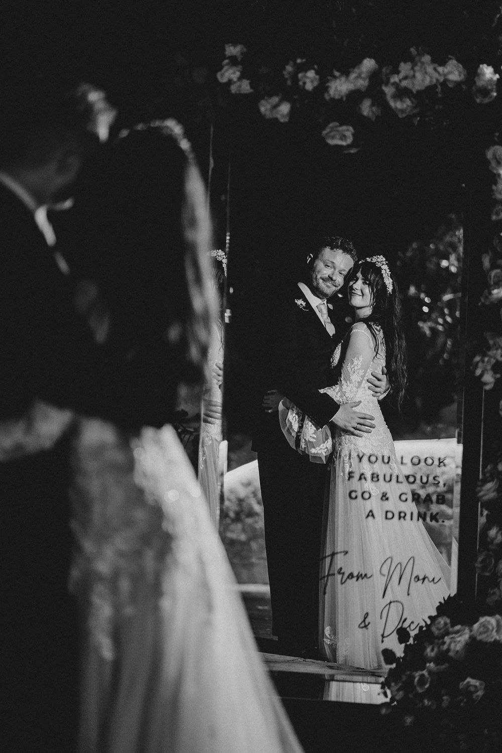 A black and white wedding reception photo showing decorative signs with handwritten messages in an elegant setting.