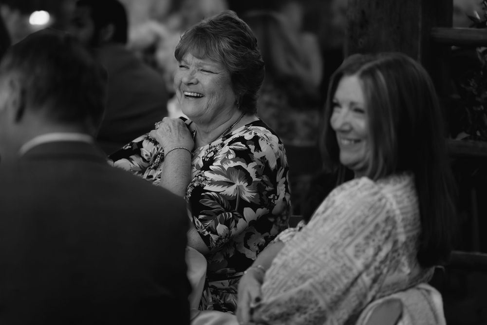 Black and white photograph showing a group of people laughing and socializing at a formal event.