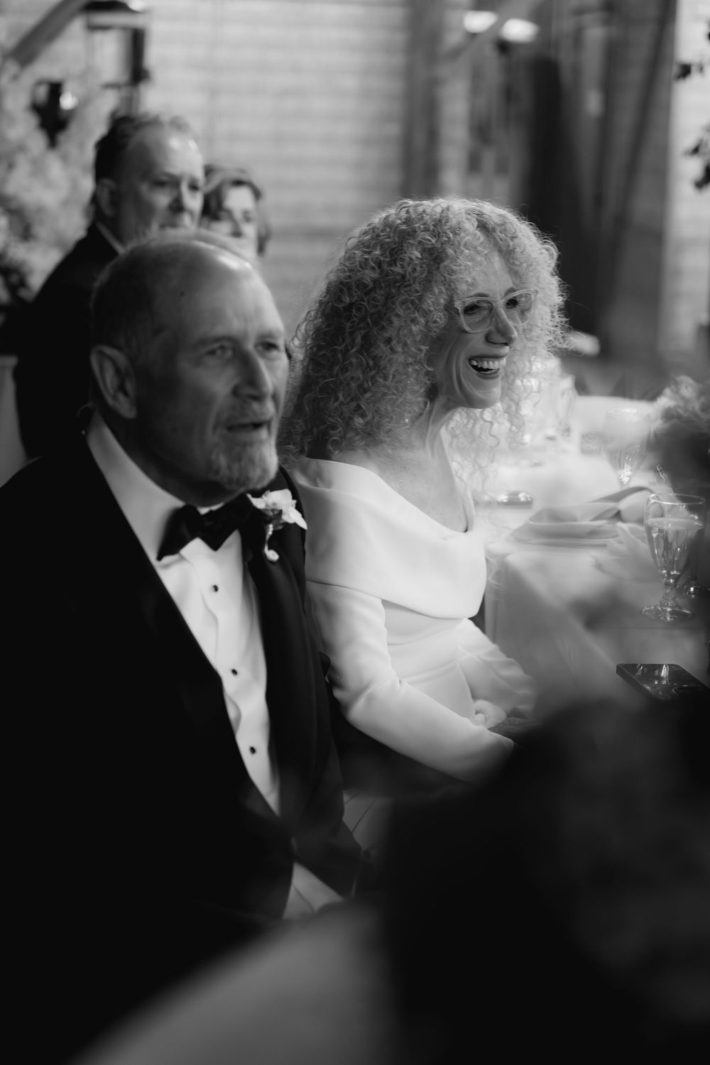 Black and white candid shot of guests in formal attire enjoying a celebratory moment at an event.