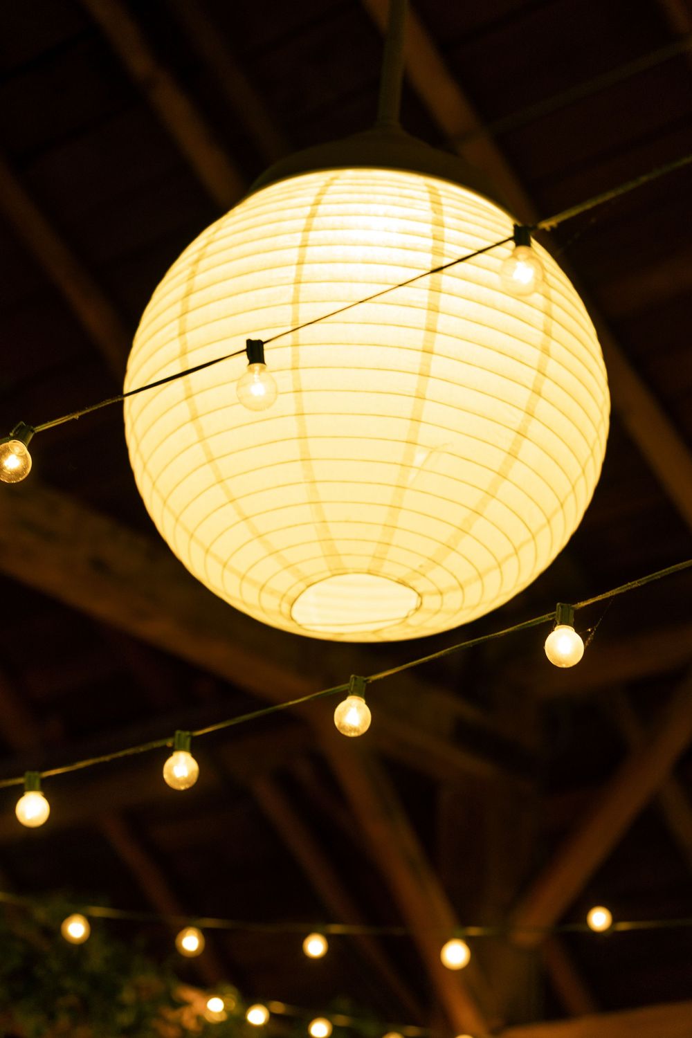 Paper lanterns and string lights create a warm ambiance at an outdoor evening event.