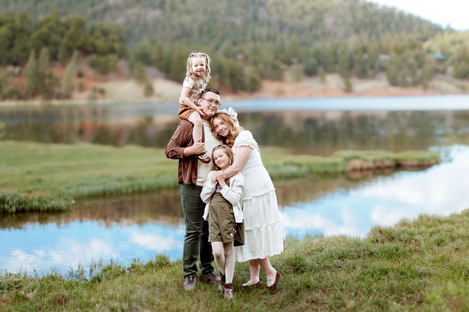 Family members posing together outdoors with natural fall foliage in the background.