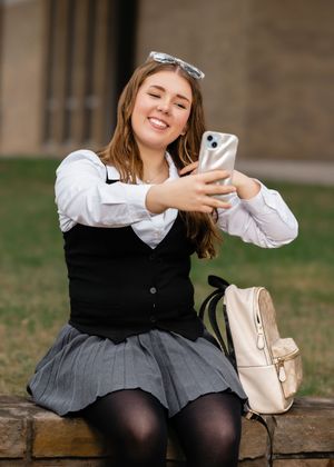 Series of casual poses while using phone on stone bench in school uniform.