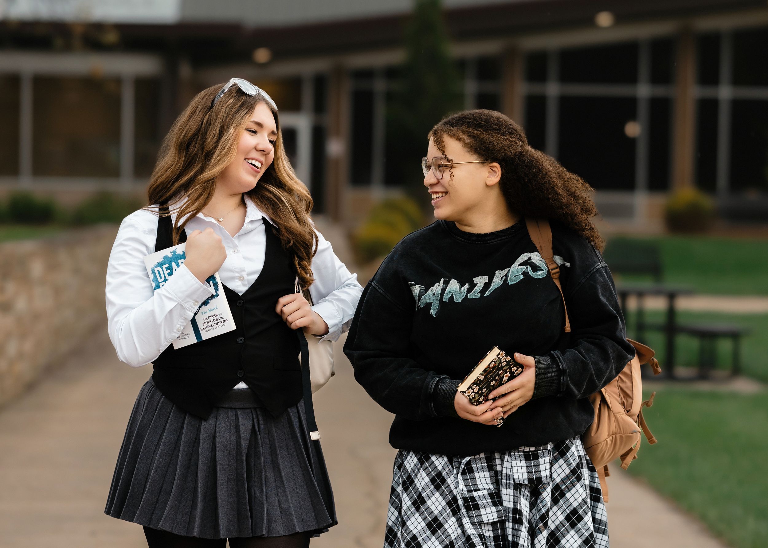 Two friends in black and white plaid outfits laughing together outdoors.