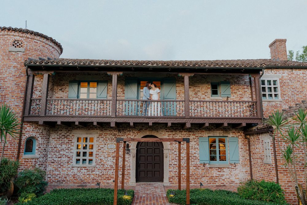 Exterior view of a rustic brick building with wooden beams and multiple windows.