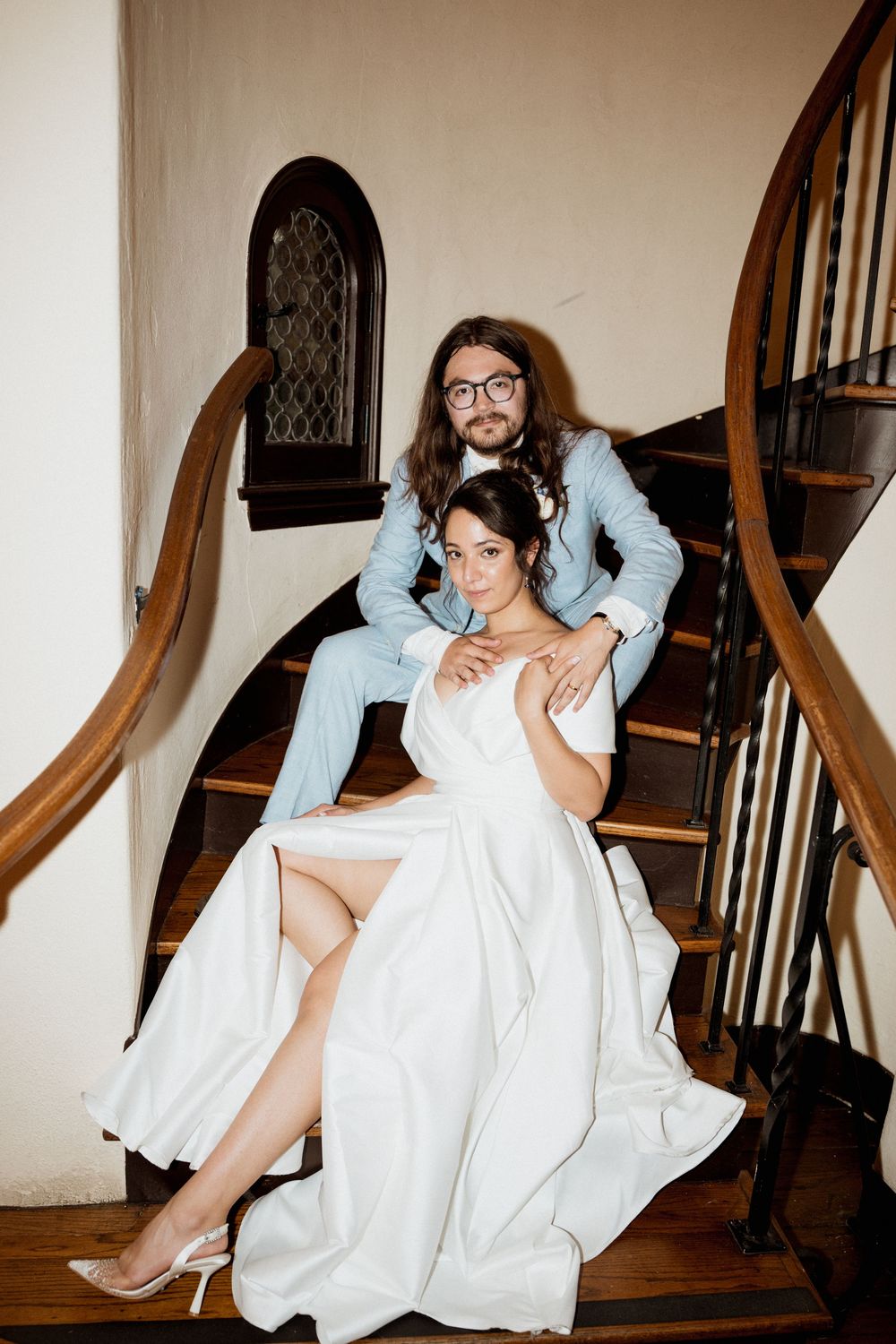 A person in a white dress and light blue jacket poses on wooden stairs in an artistic photo series.