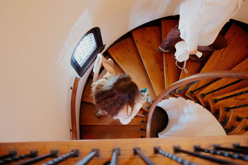 Wedding dress hanging elegantly against wooden staircase in natural light.