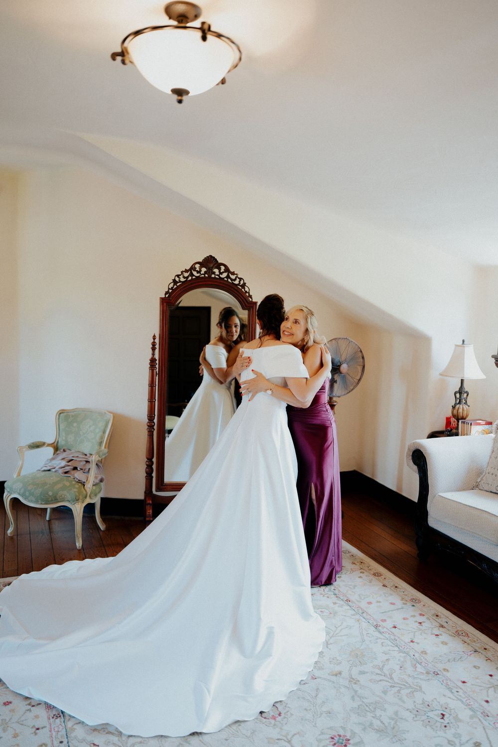 A wedding dress preparation sequence showing the elegant white gown with a flowing train in a bright hotel room.