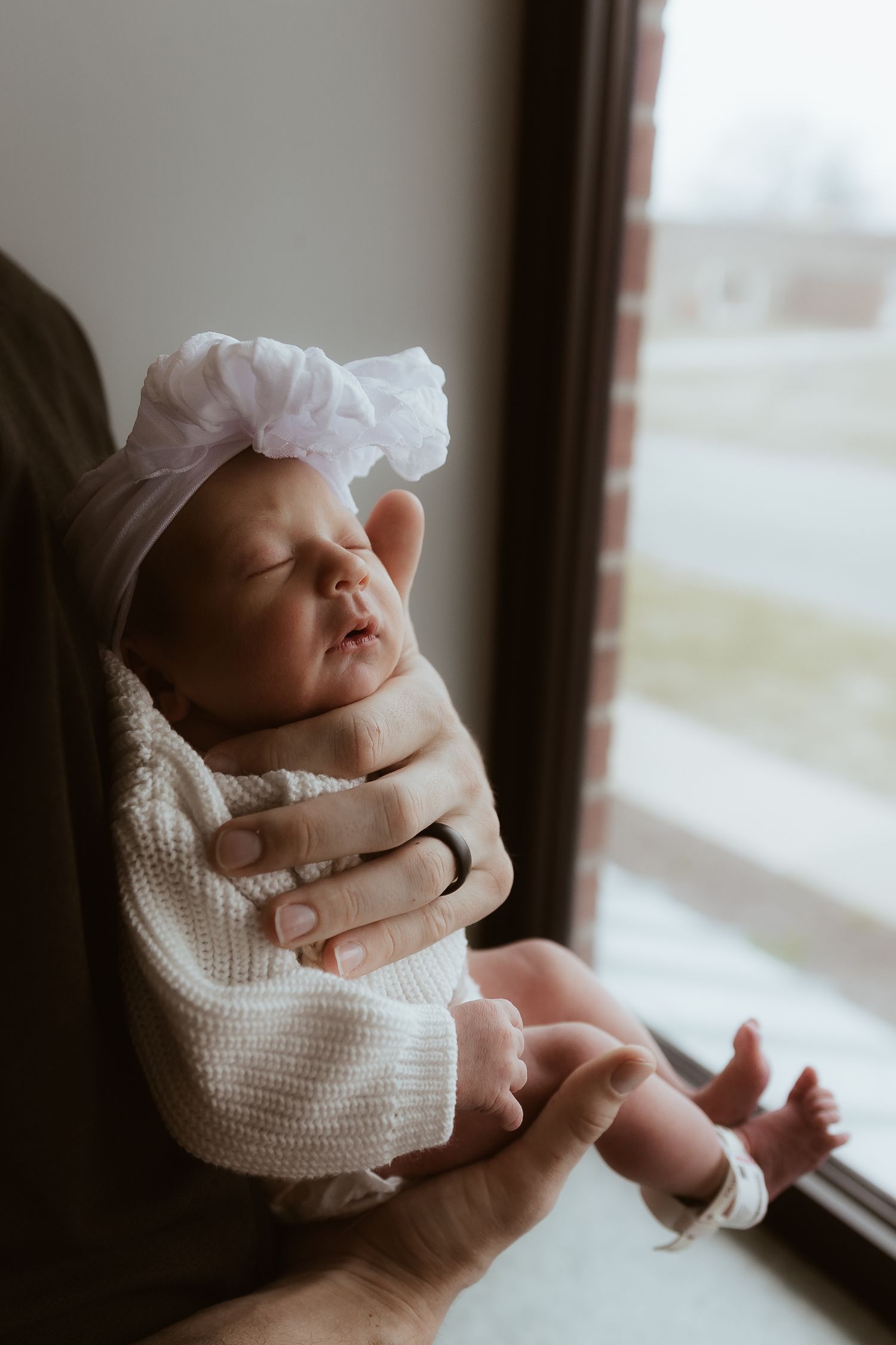 Close-up series of tiny baby feet wrapped in white cloth against a textured cream-colored knit blanket background.