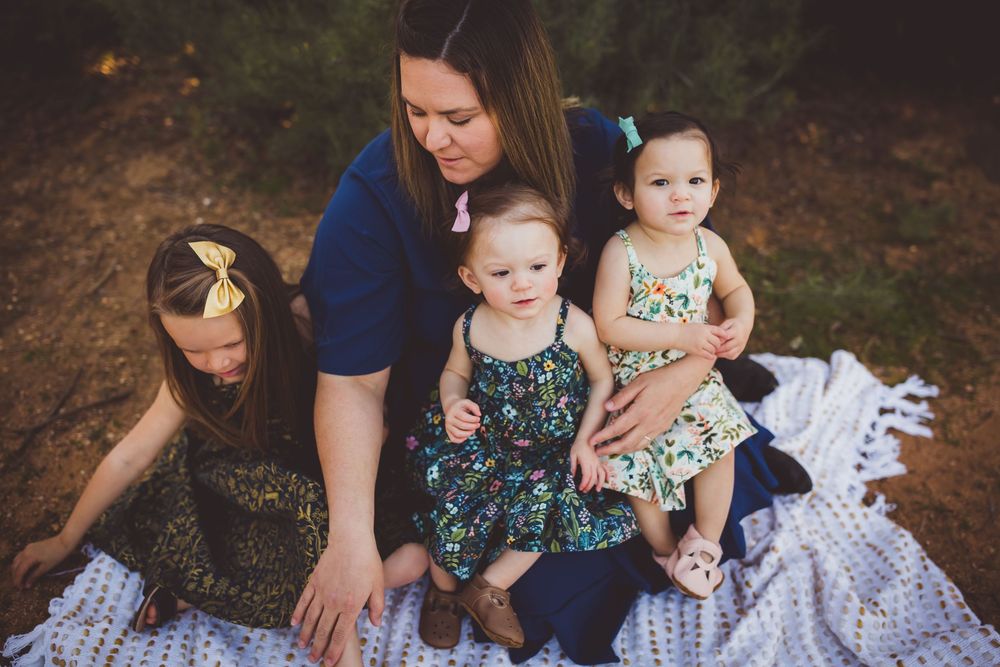 A family sits together on a blanket outdoors during a photo session in autumn.