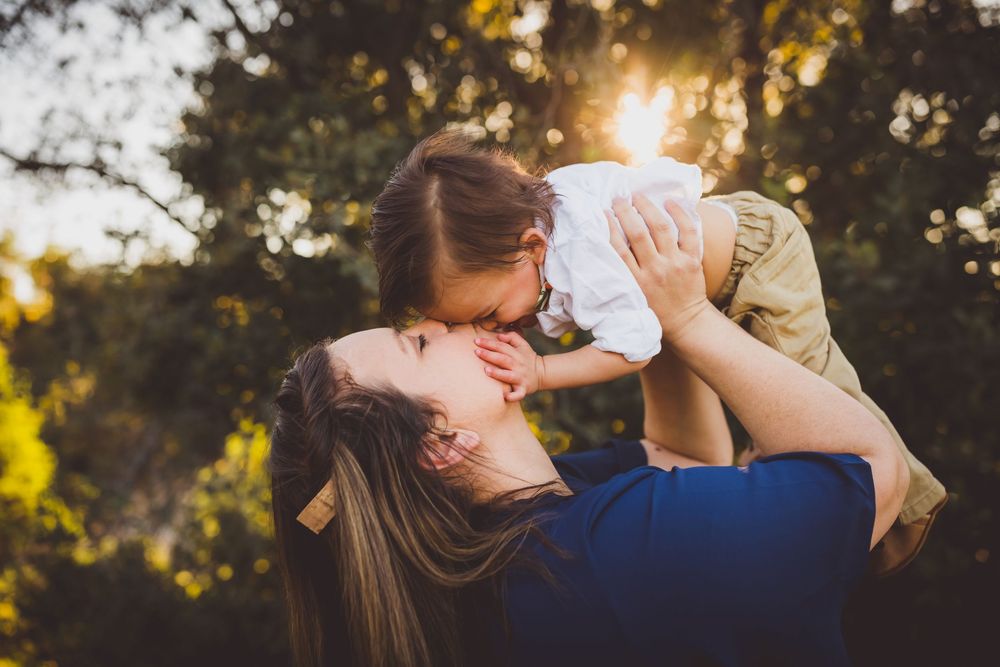 Silhouetted family members embrace during a golden hour outdoor photo session with sunlight filtering through trees.