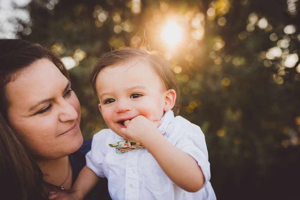 A tender moment between parent and child captured in golden sunlight during an outdoor portrait session.