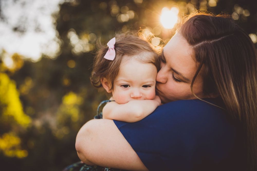 A tender moment between parent and child is captured during golden hour in a natural outdoor setting.