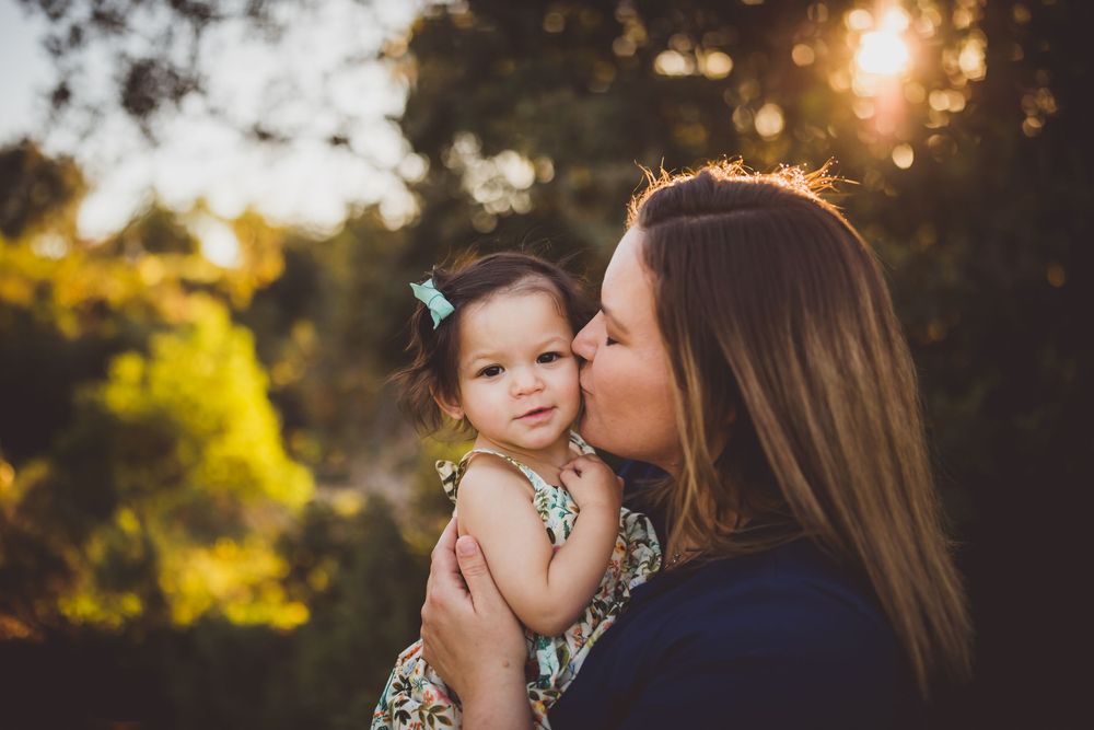 A loving embrace during sunset with glowing yellow bokeh and trees in the background.