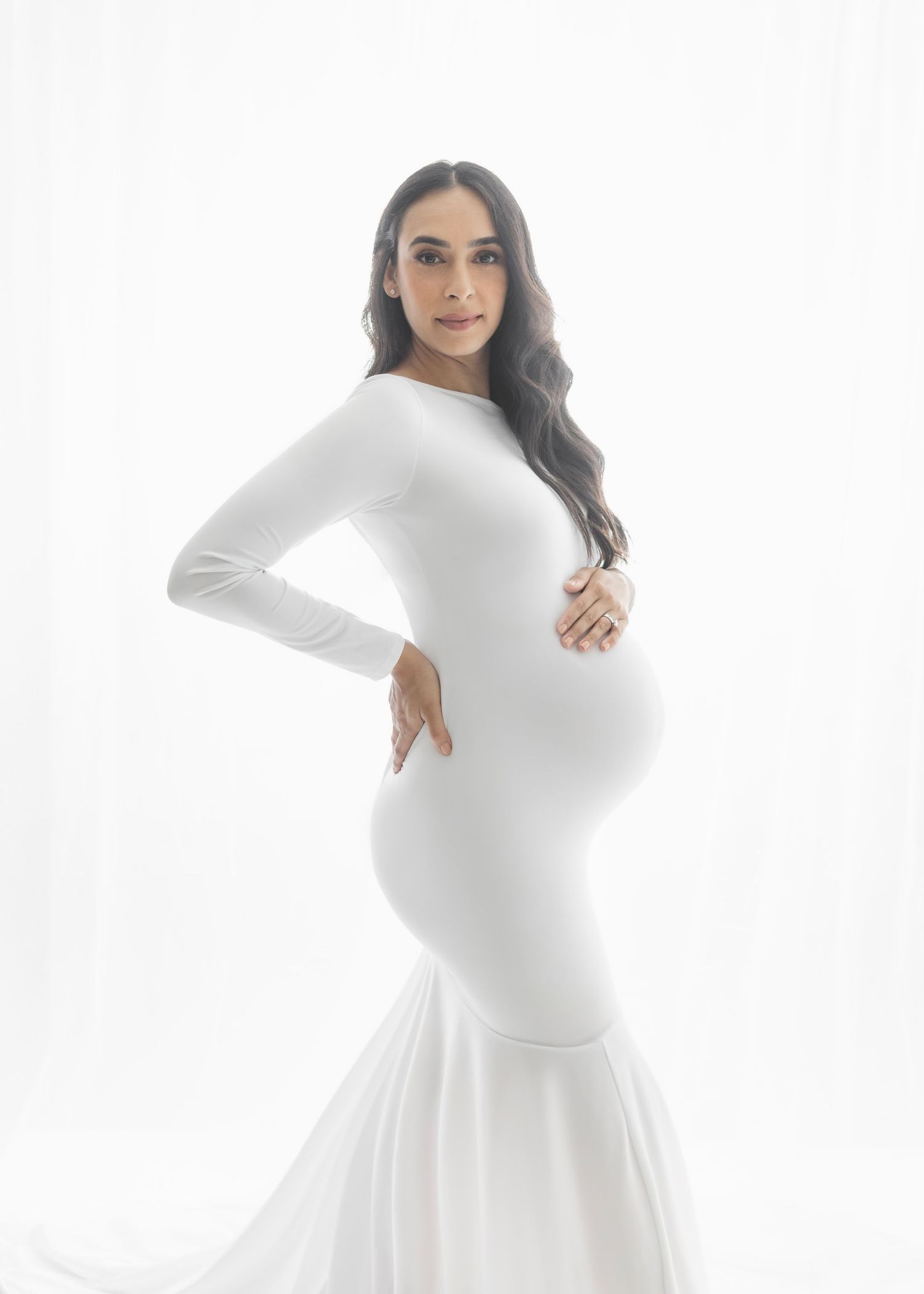 Woman in white long sleeve maternity dress poses against white background in four different poses.