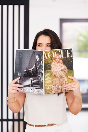 Person holding up fashion magazines to cover face in modern office setting. Personal Branding Photography.
