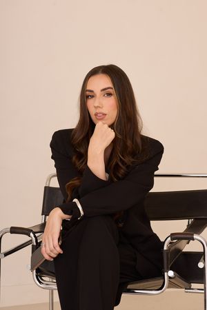 Fashion portrait series showing contemplative poses in black outfit on modern chair.