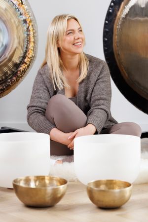 Relaxed portrait sitting with meditation bowls in healing space with decorative gongs. Personal Branding Photography.