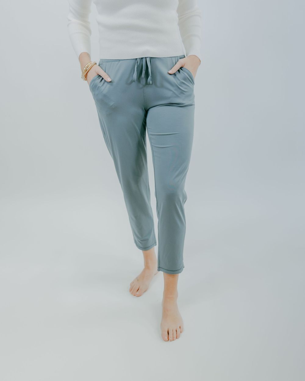 Light blue sweatpants with pockets and drawstring waist shown from different angles against a white background.