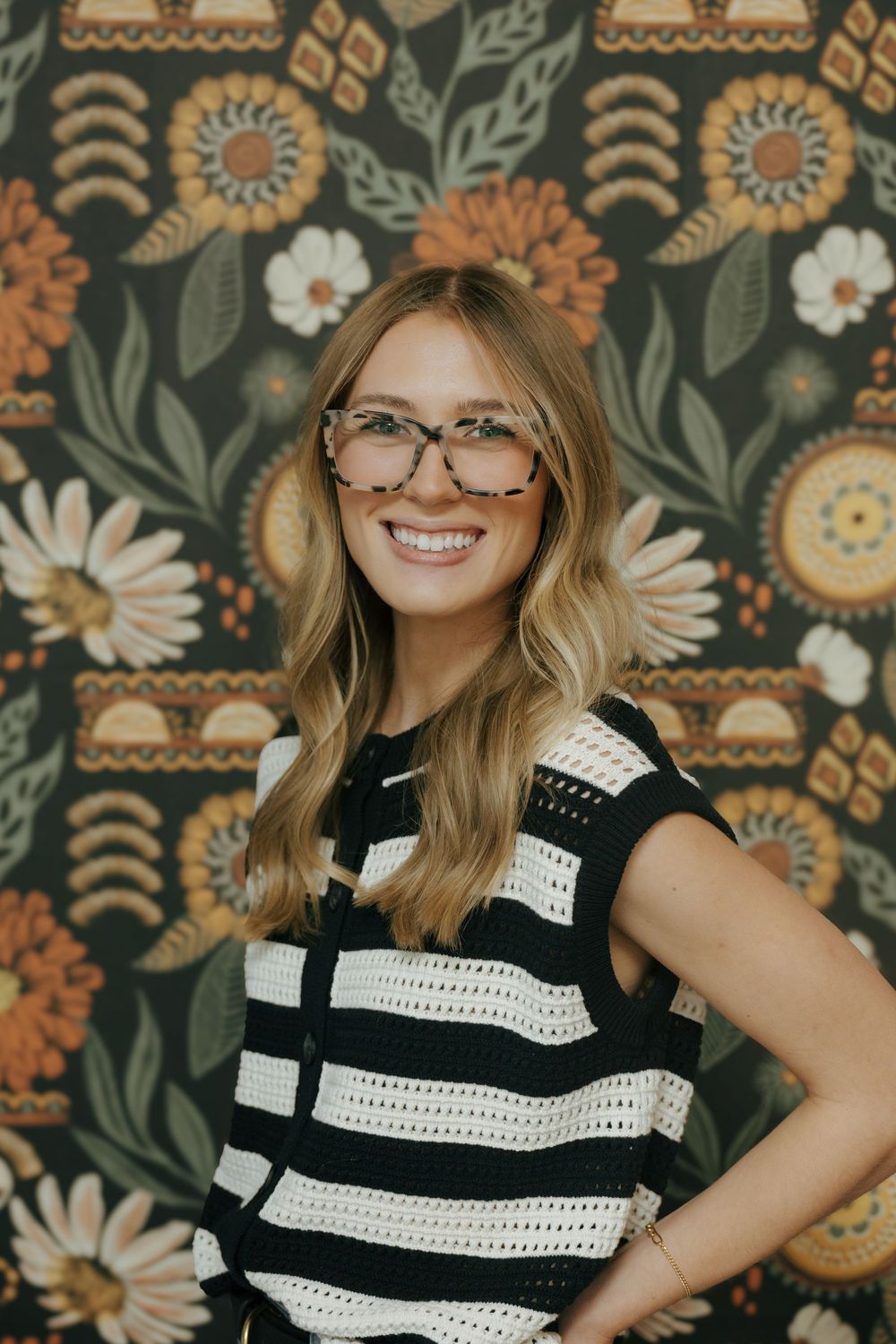 Striped black and white sweater against a floral patterned wallpaper with orange and green retro designs.
