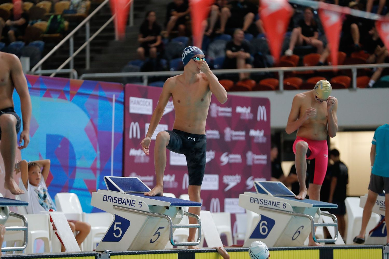 Swimmers prepare to dive from starting blocks at competitive swimming event.